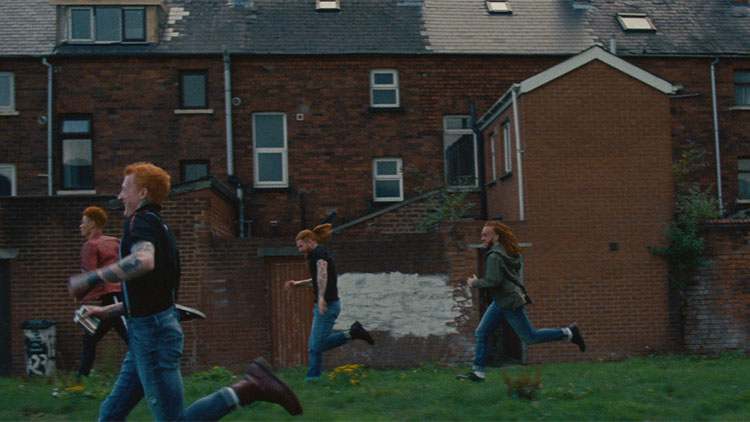 a group of kids running through a Scottish neighborhood