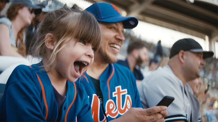 a father and his daughter cheering in a baseball stadium