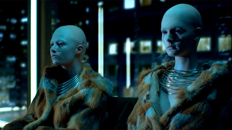 two alien women with bluish skin and completely bald heads