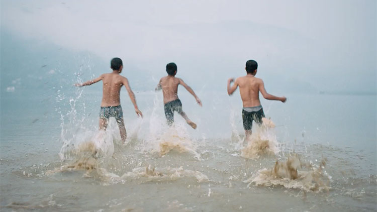 three young boys running into the ocean