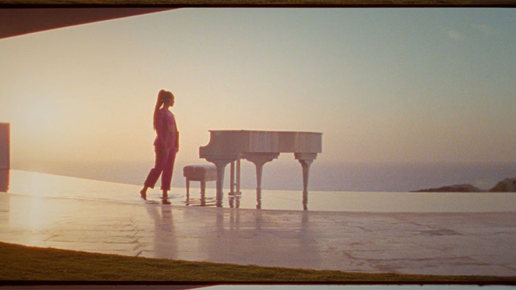 a woman standing in front of a piano on a large patio overlooking the ocean