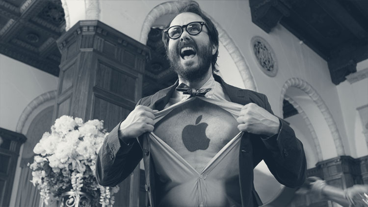 a bearded man ripping open a dress shirt with an Apple Computer logo on his chest