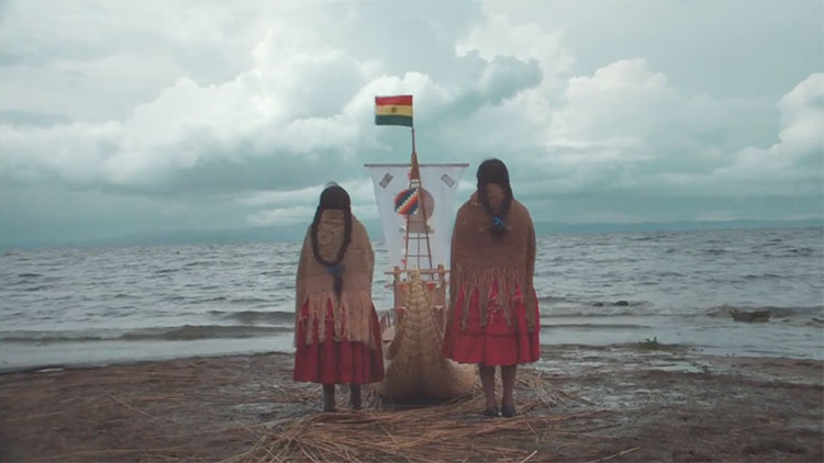 two indigenous South American women standing on a beach looking out over the ocean